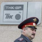 A police officer walks past a plaque of the oil firm TNK-BP at its headquarters in Moscow