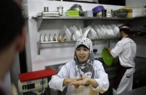 A hearing impaired employee uses sign language to communicate with a co-worker in the kitchen of a restaurant in Gaza