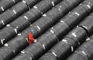 A worker checks on coils of steel at a factory in Dalian